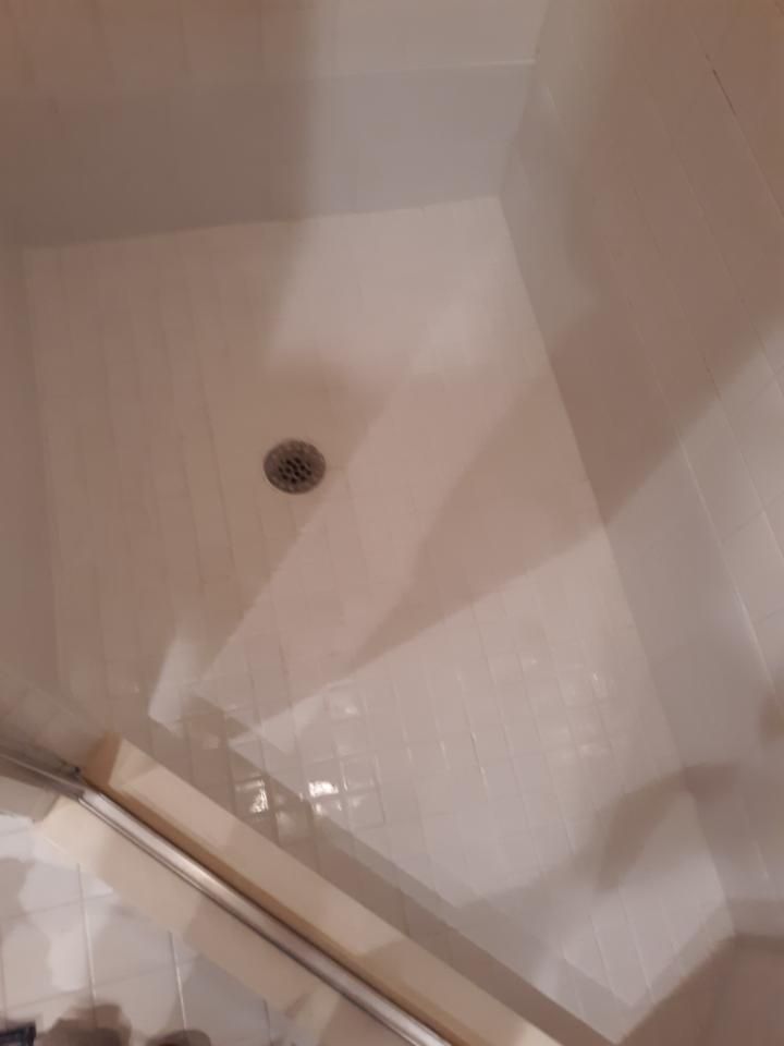 A shower stall with a drain on the floor in a bathroom.