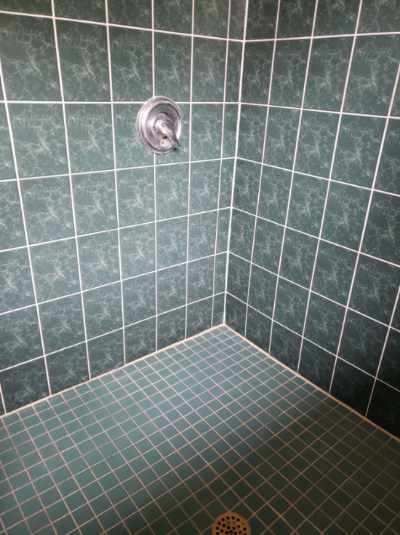 A shower with green tiles on the walls and floor.