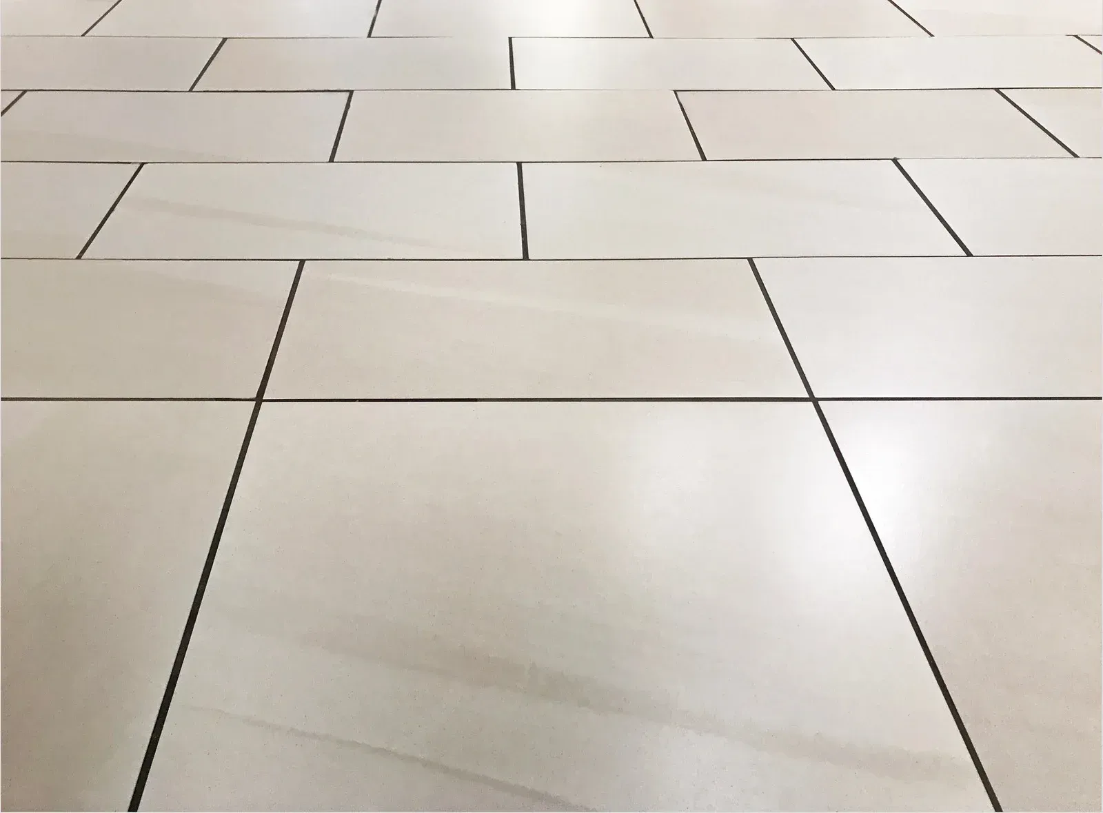 A person is holding a trowel over a white tile floor