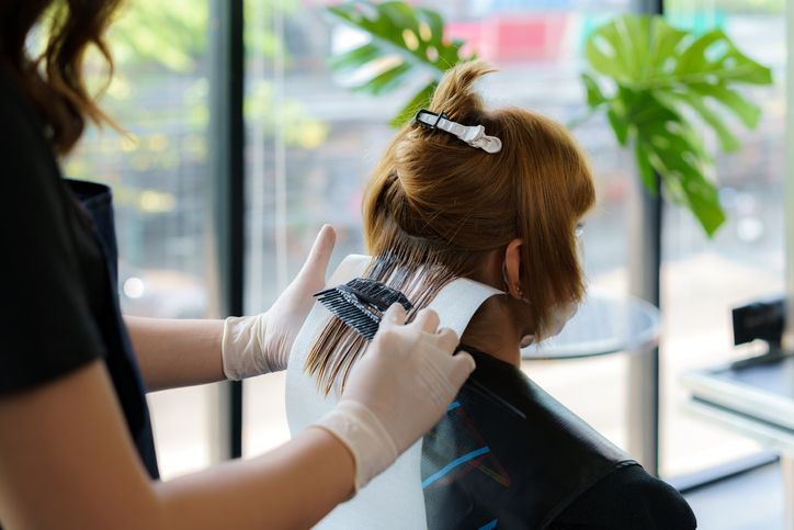 hairdresser thoroughly dyeing hair of female client