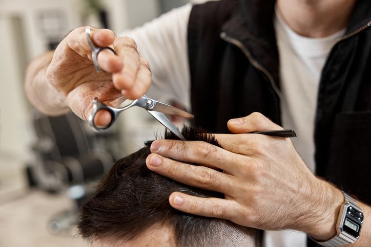 Professional hairdresser does haircut for  bearded man