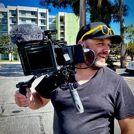 A man is carrying a camera on his shoulder.