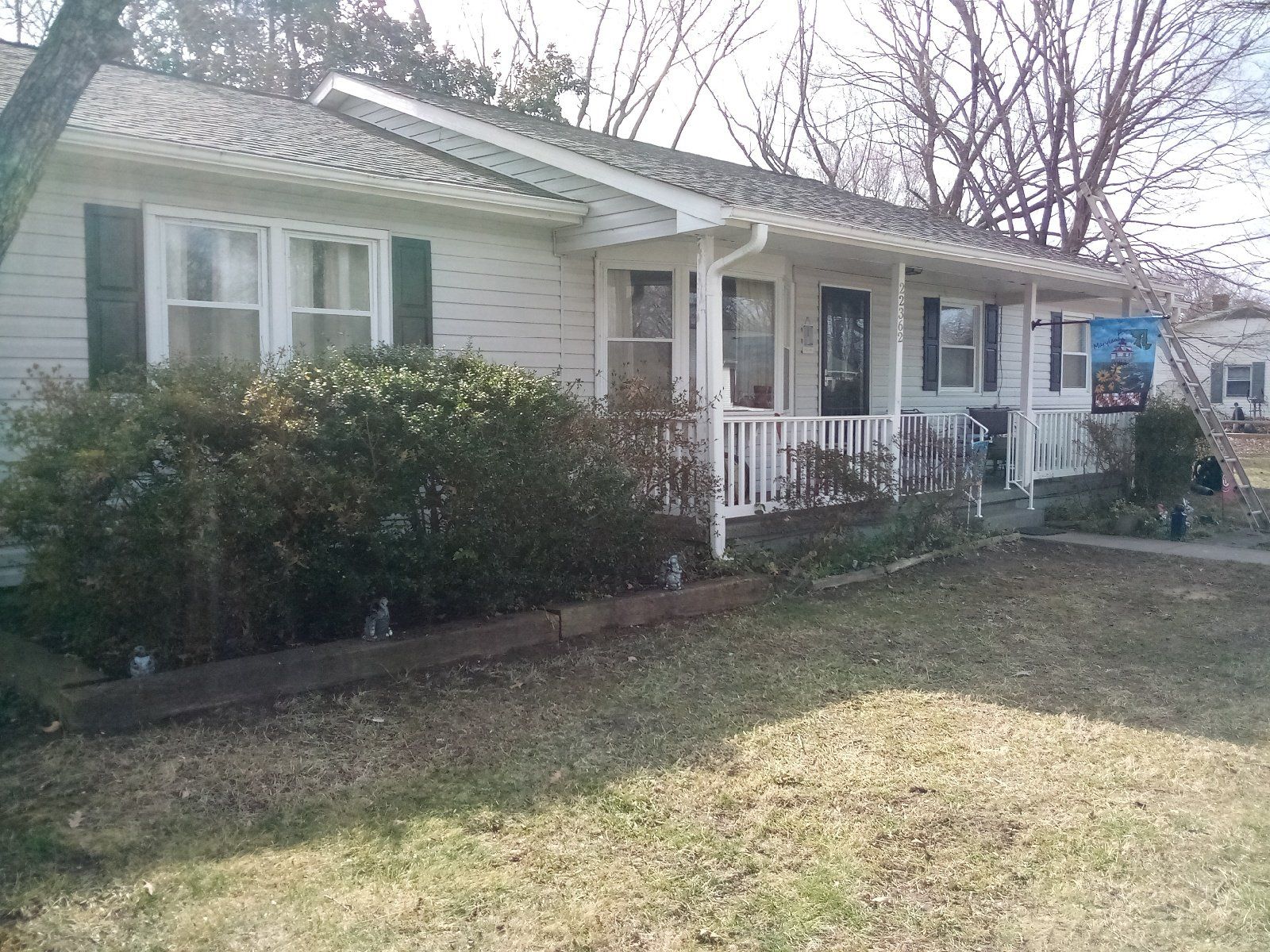 A white house with black shutters and a porch is for sale.