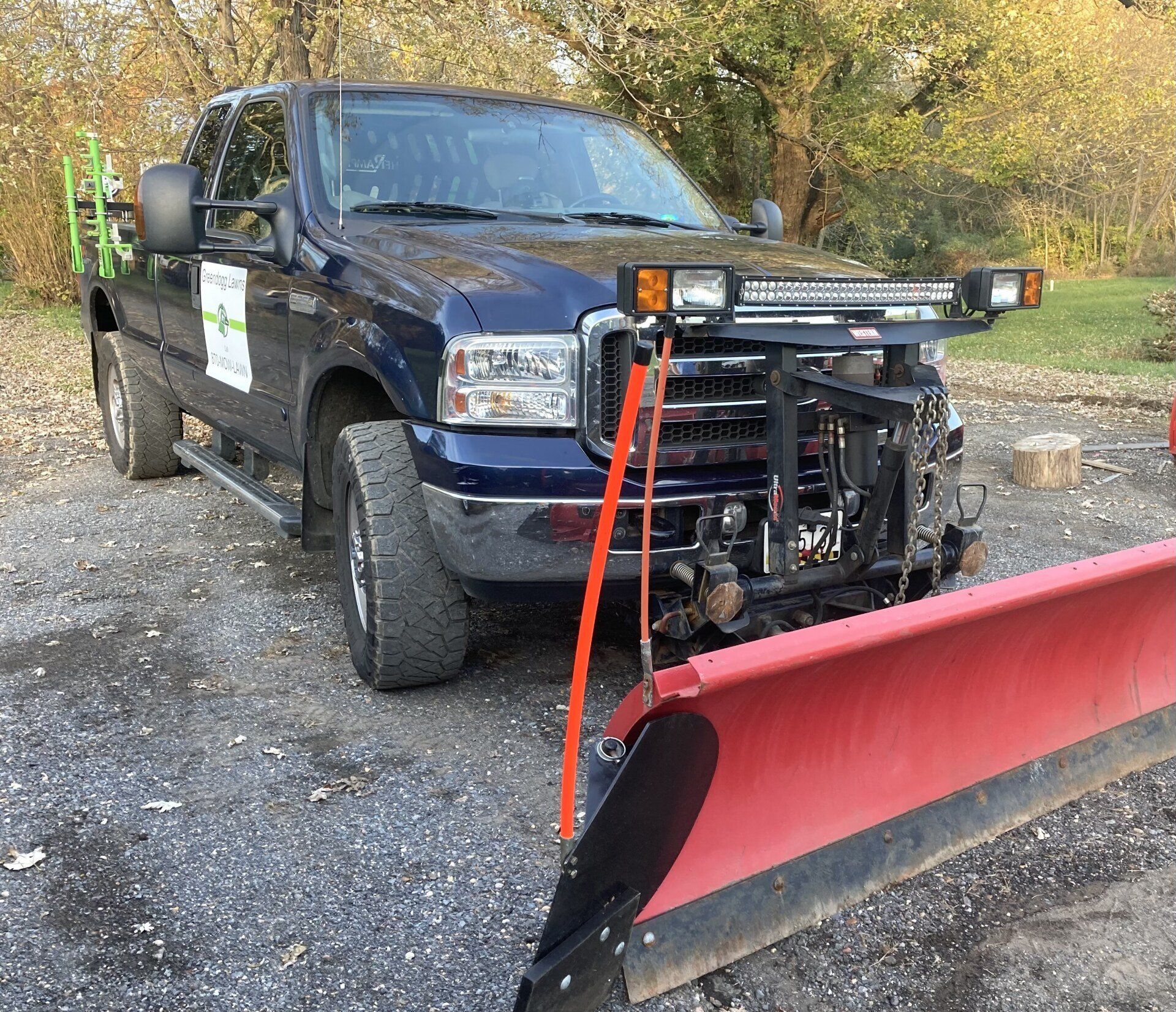 A blue truck with a red snow plow attached to it.