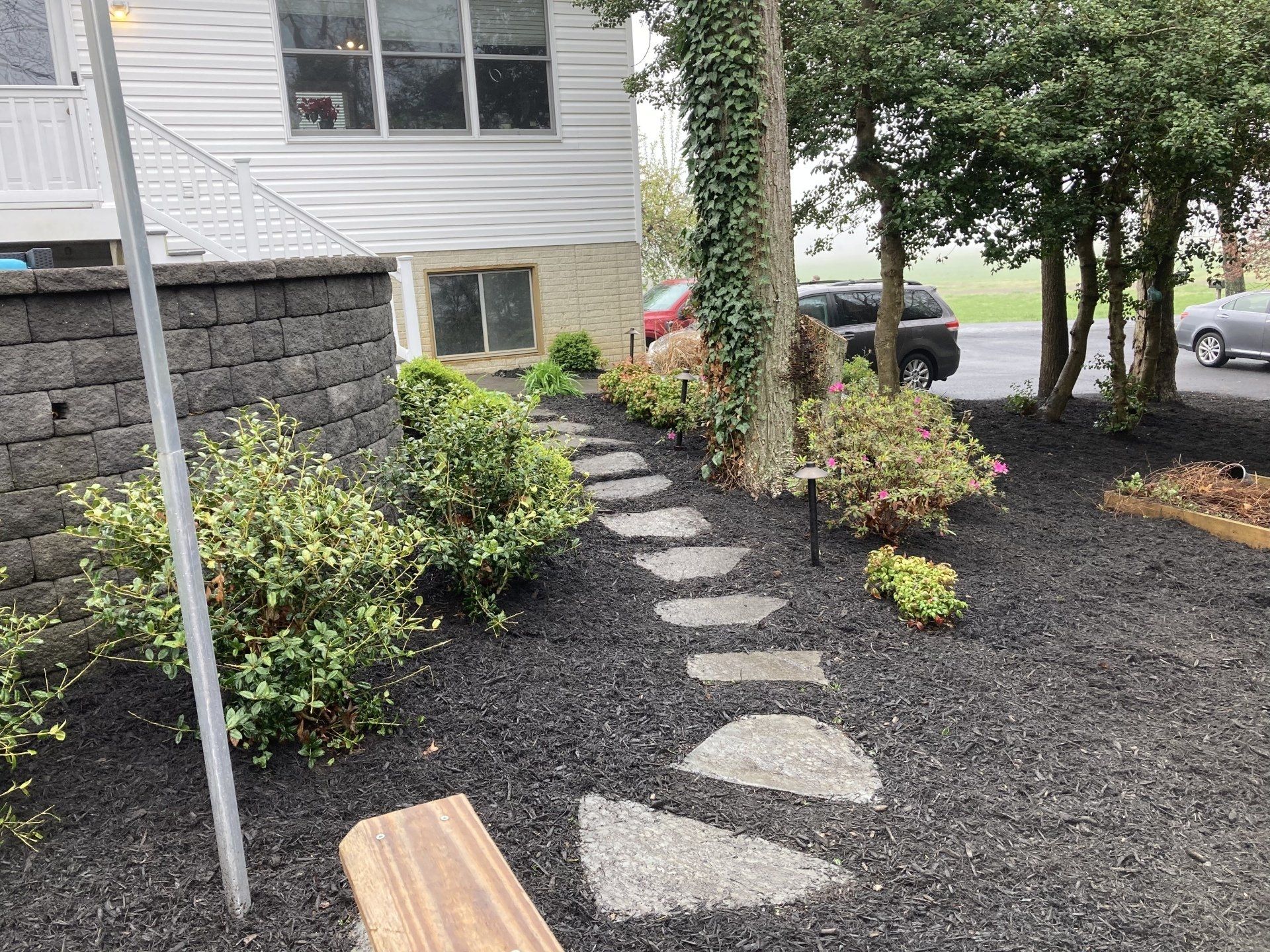 A stone walkway leading to a house with a car parked in the driveway.