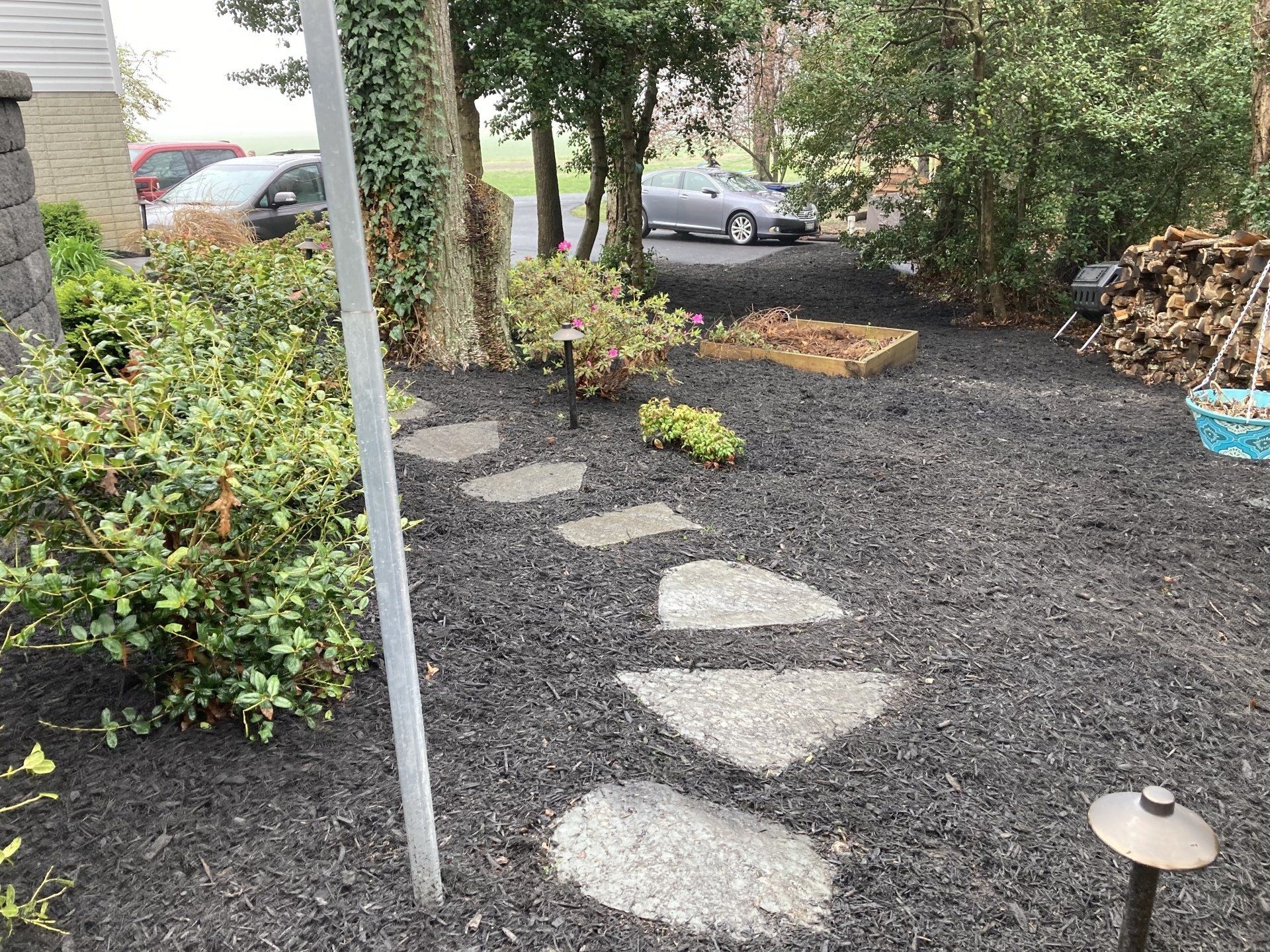 A stone walkway in a backyard with a car parked in the background.