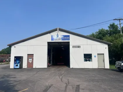 Small beige auto repair shop with open garage bay and sign above the entrance