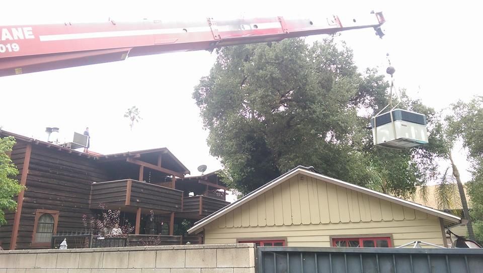 A crane is lifting a container over a house.