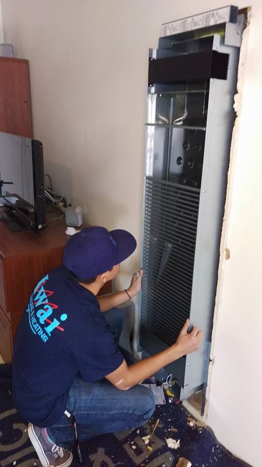 A man is working on a refrigerator in a room.