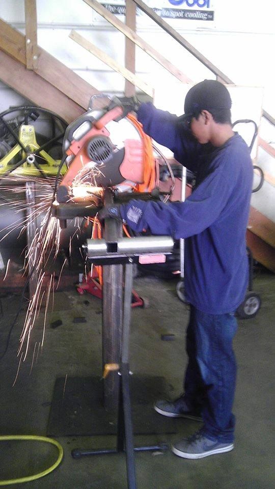 A man is using a machine to cut a piece of metal.