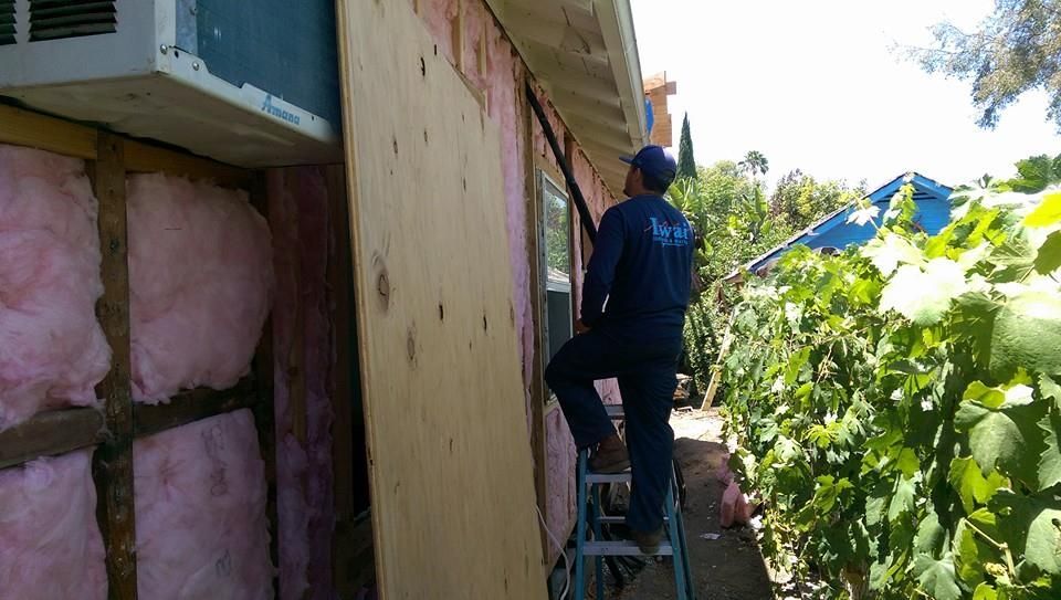A man is standing on a ladder on the side of a building.