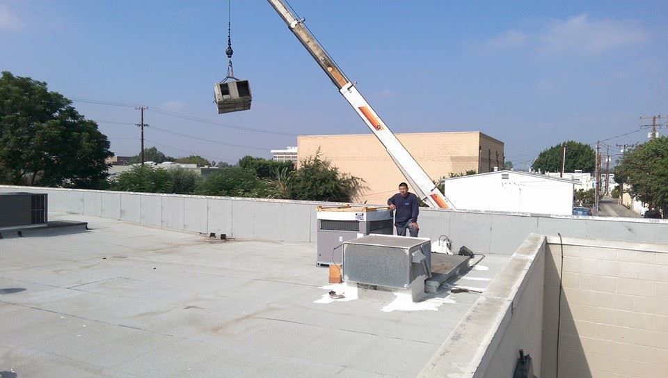 A man is standing on a roof next to a crane