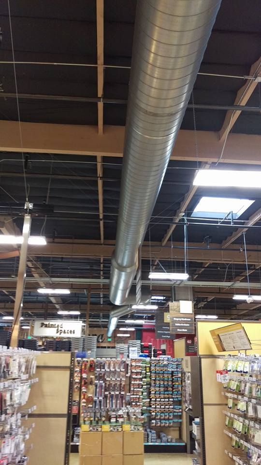 A large metal pipe is hanging from the ceiling of a store.