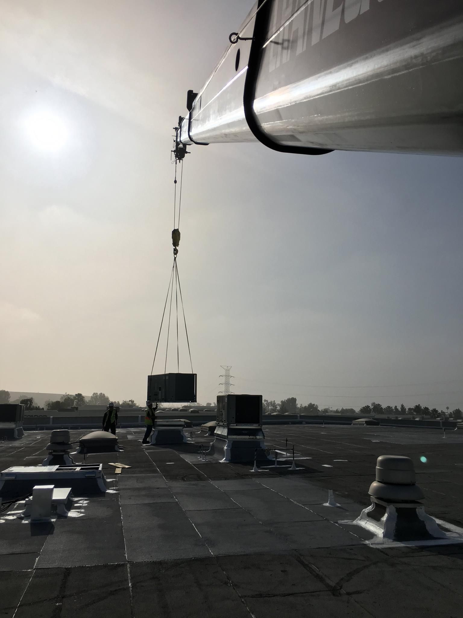 A crane is lifting a large object from the roof of a building.