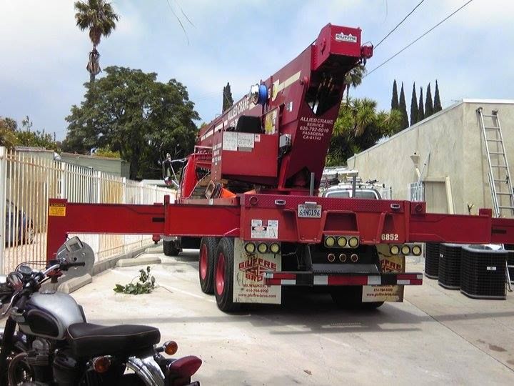 A red truck with a crane on the back is parked next to a motorcycle