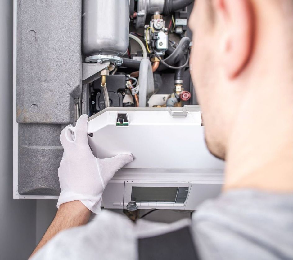 A man wearing white gloves is working on a boiler.