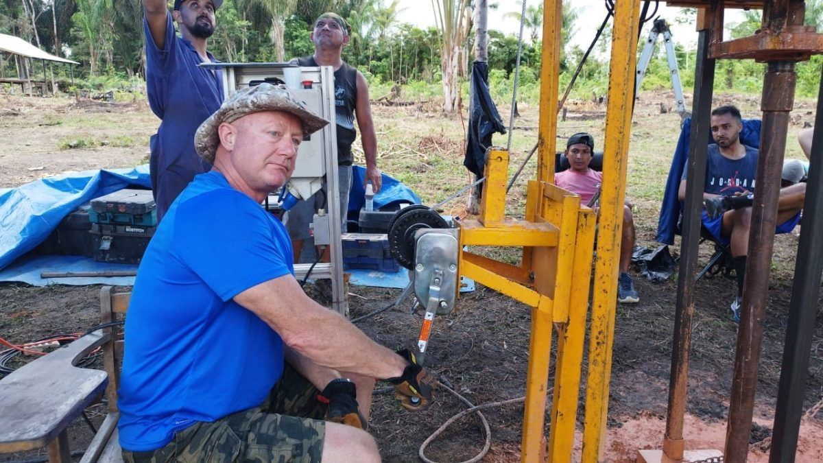 Group of people smiling and talking outdoors, possibly volunteering.