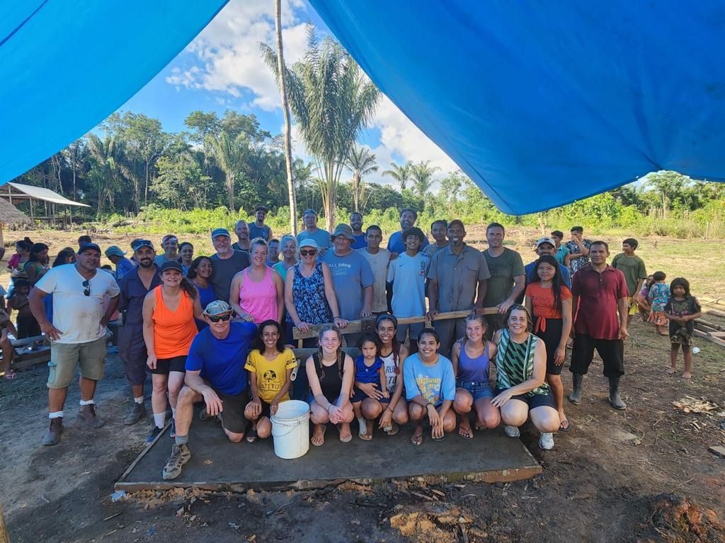 People sorting food items in a food bank, with shelves stocked in the background.