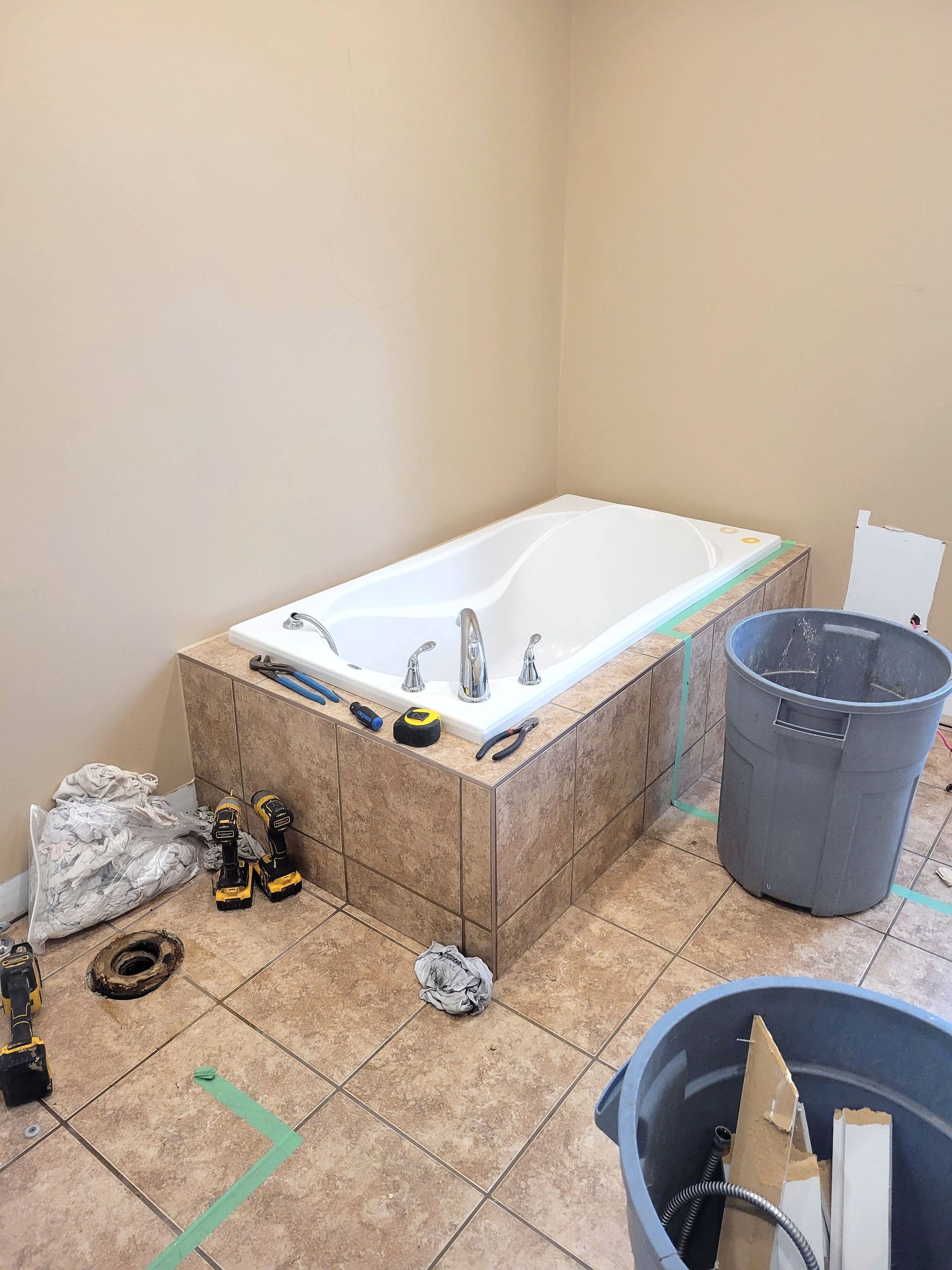 Une personne se tient sur une échelle, en train de réparer une plaque de plâtre sur un mur intérieur inachevé d'une pièce en construction.