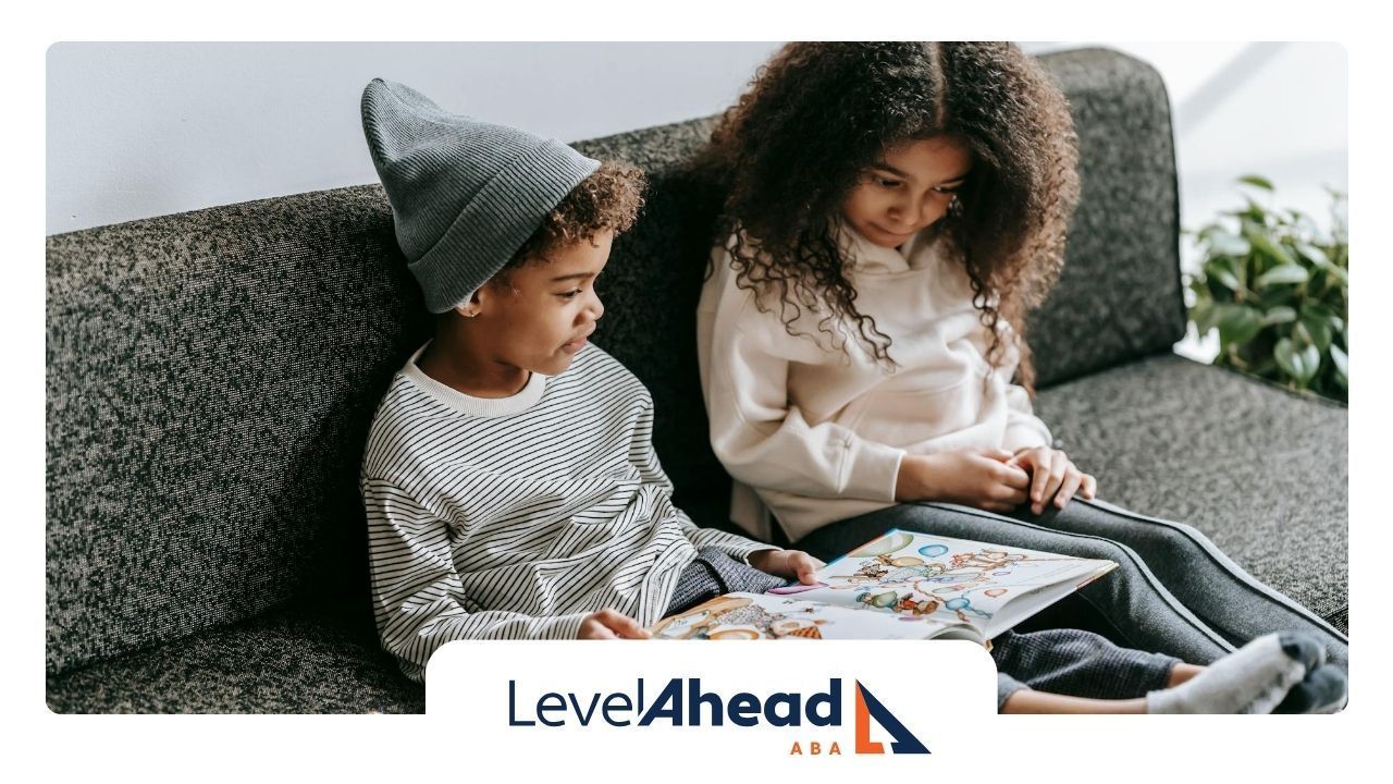 Two children with autism sitting on couch, attentively reading a book together at home in Nebraska.