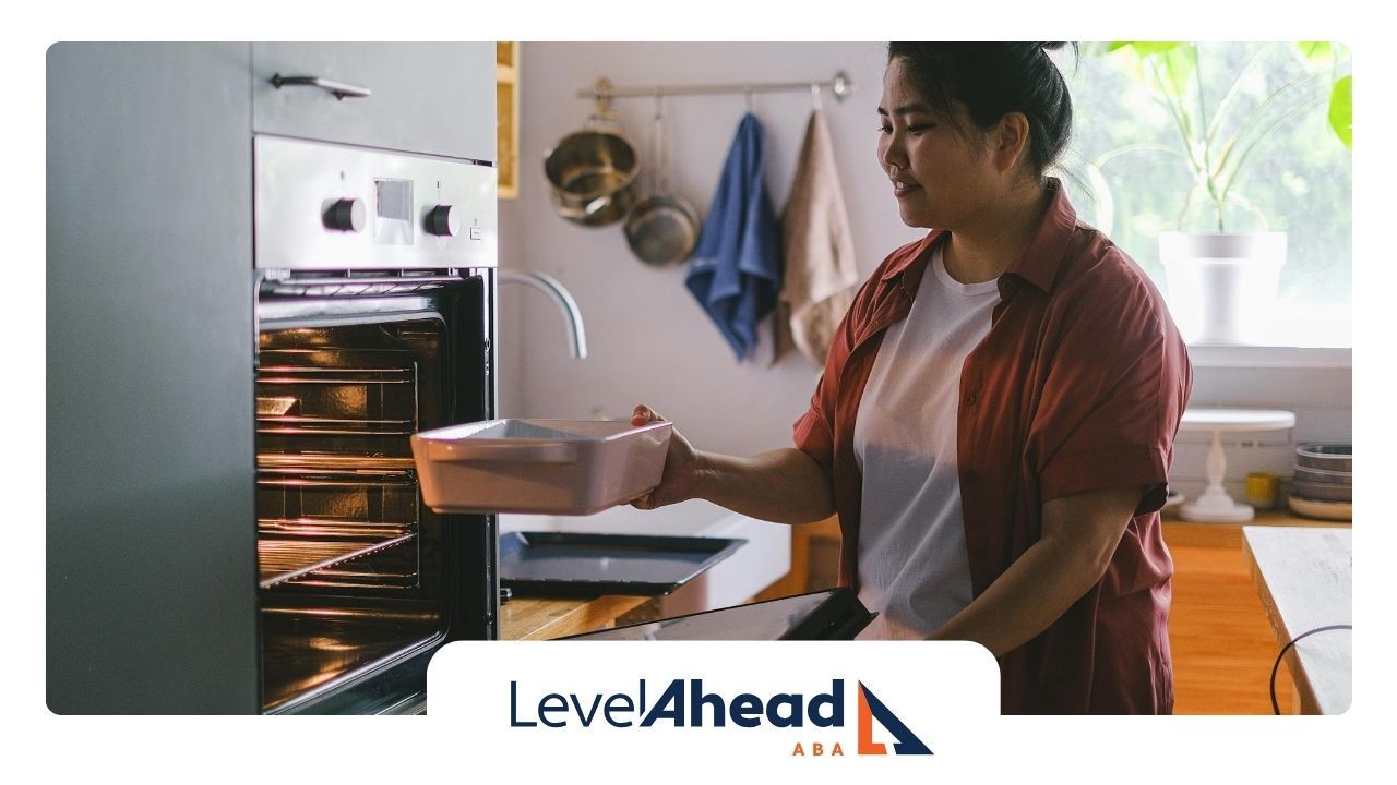 An autistic adult placing an autism-friendly dish into an oven in a cozy kitchen at home in NE.