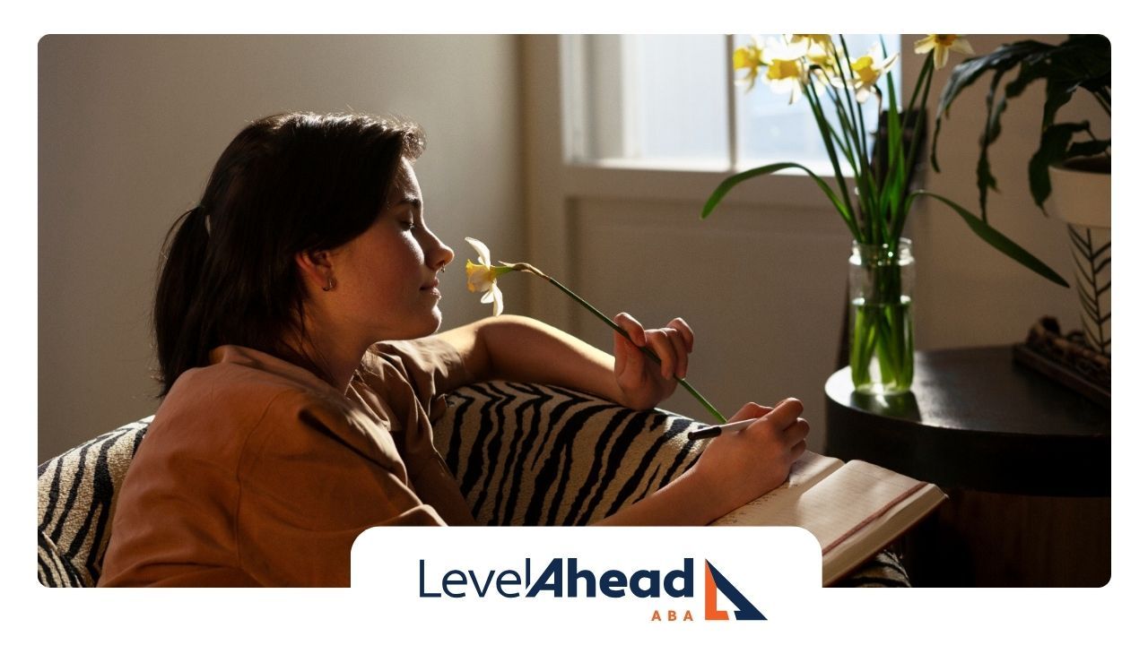 A woman with autism is sitting on a couch holding a flower.