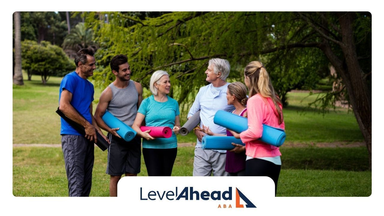 A group of autistic adults and their instructors are holding yoga mats during a retreat.