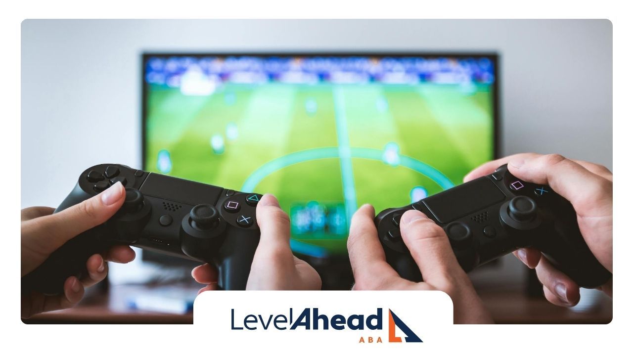 Hands of autistic adult holding video game controllers in front of a TV screen playing sports game.