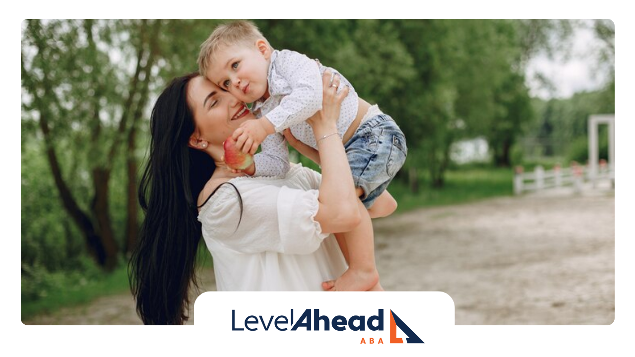 A mother is holding her son in her arms in a park.