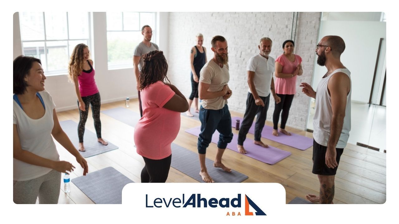 A group yoga class consisting of autistic adults in a bright studio.