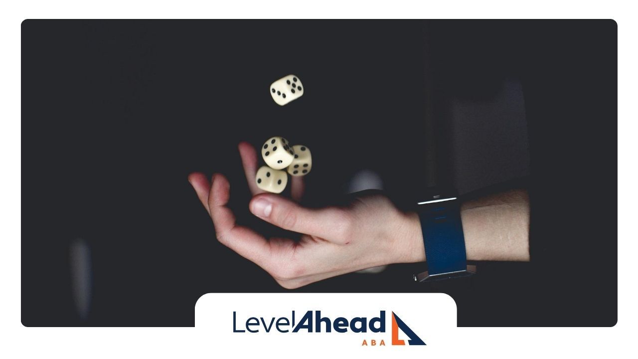 Autistic adult's hand tossing five dice in mid-air, against a dark background in Nebraska.