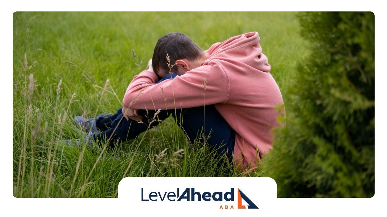 A man in a pink hoodie is sitting on the grass.