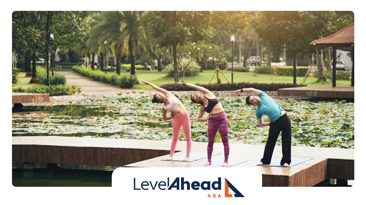 A group of autistic individuals doing yoga stretching by the lake