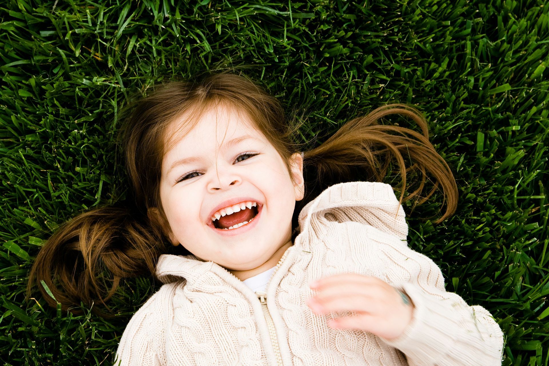 A little girl laying on the grass smiling