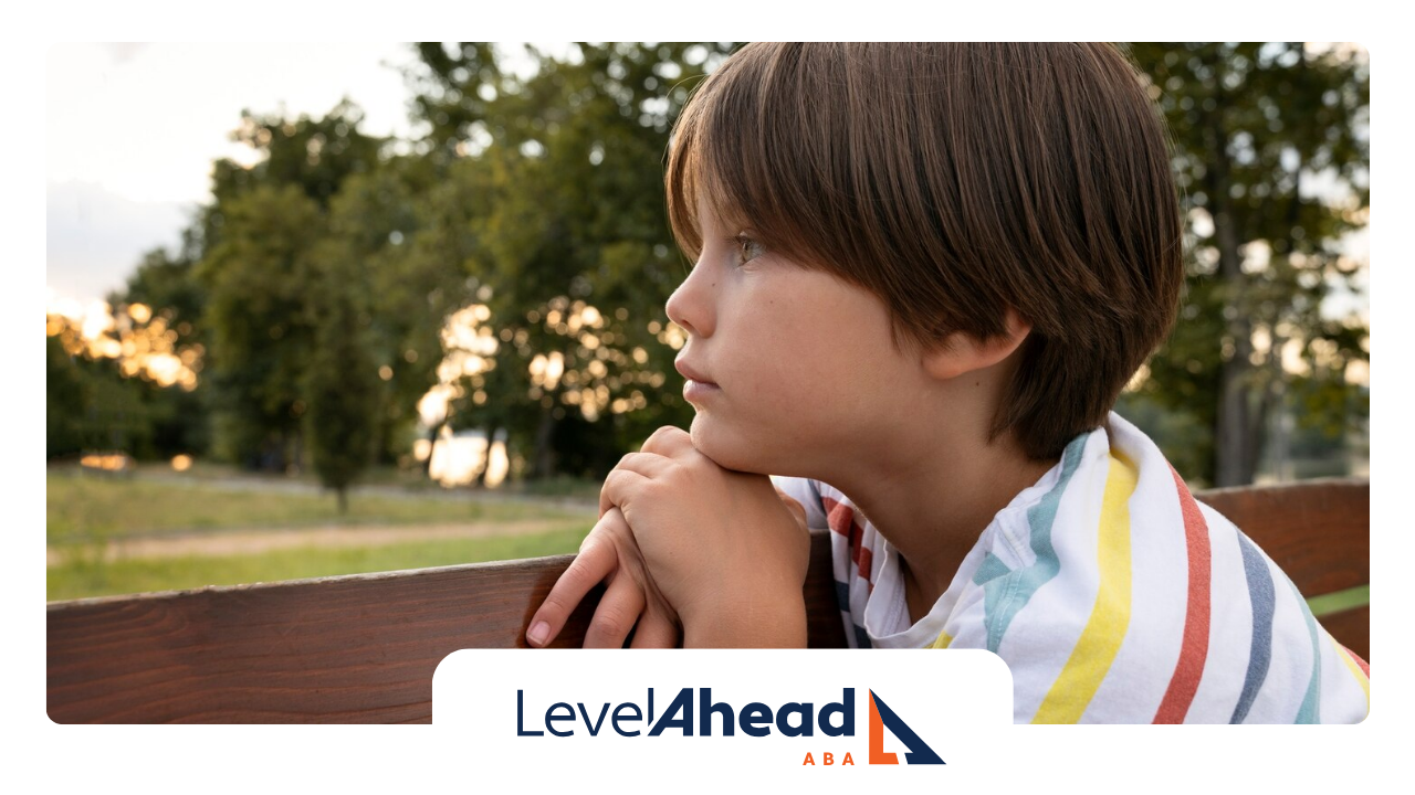 A boy with autism is sitting alone on a bench looking away