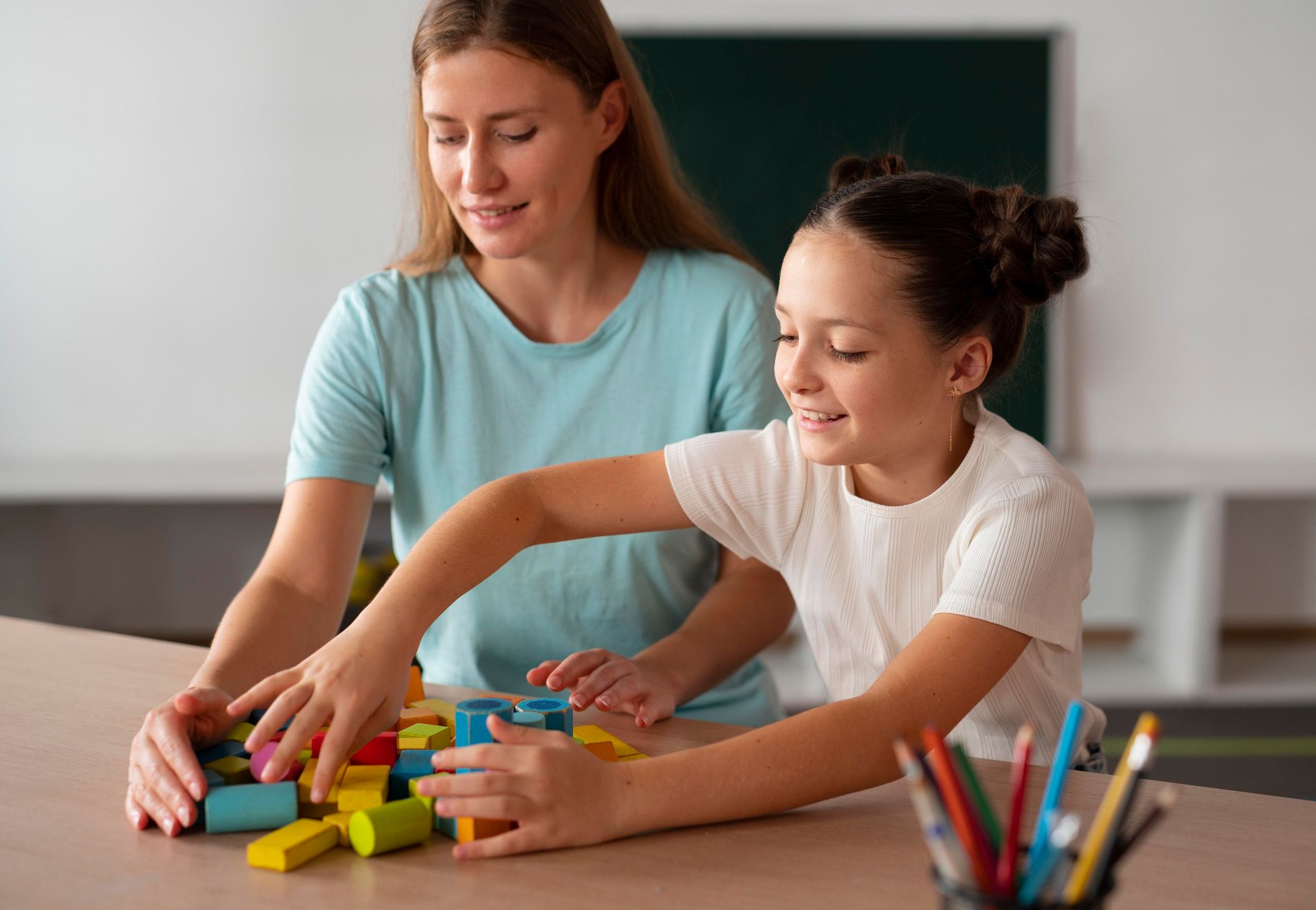 A woman and a little girl sitting at a table painting with watercolors 