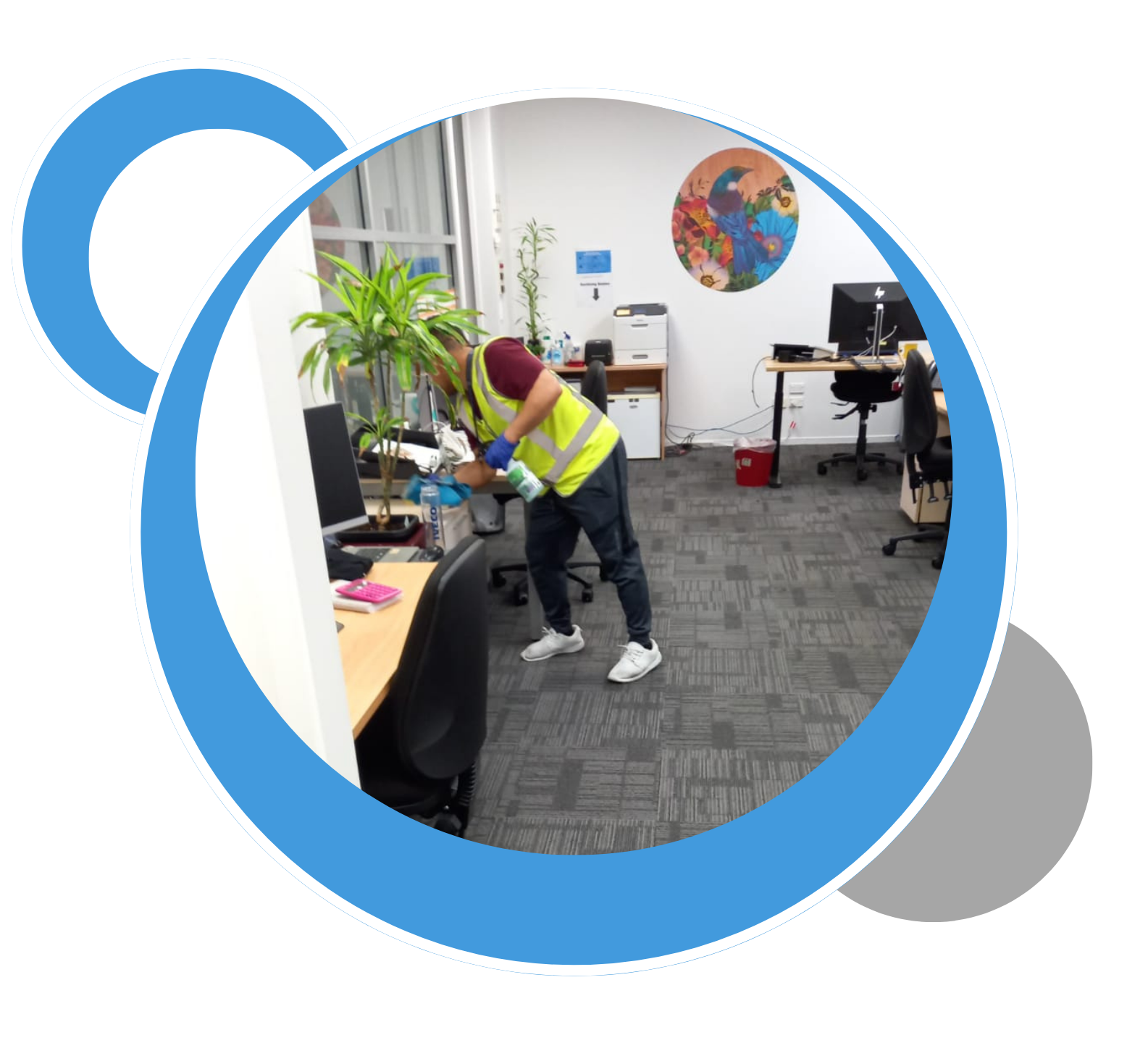 A man in a yellow vest is cleaning the floor of an office.