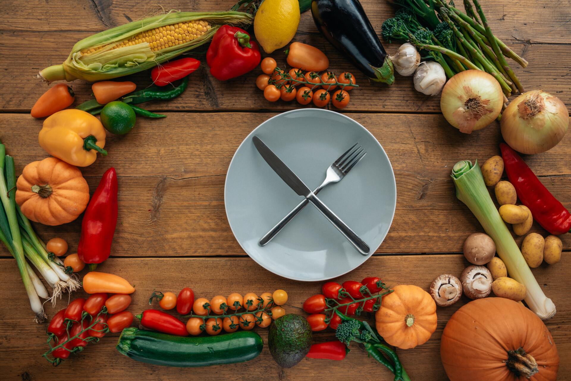 Plate with cutlery surrounded by vegetables