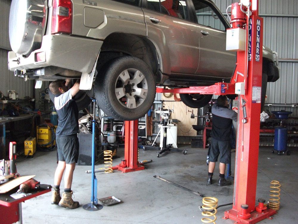 Man Is Working On A Car On A Lift In A Garage — Gympie Diesel & Dyno Centre in Gympie, QLD