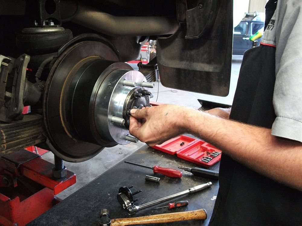 Man Is Working On A Brake Disc On A Truck — Gympie Diesel & Dyno Centre in Gympie, QLD