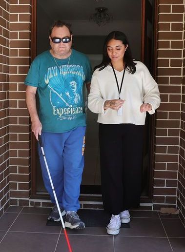 A man with a cane is walking next to a woman.