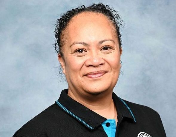 A woman wearing a black shirt and a blue shirt is smiling for the camera.