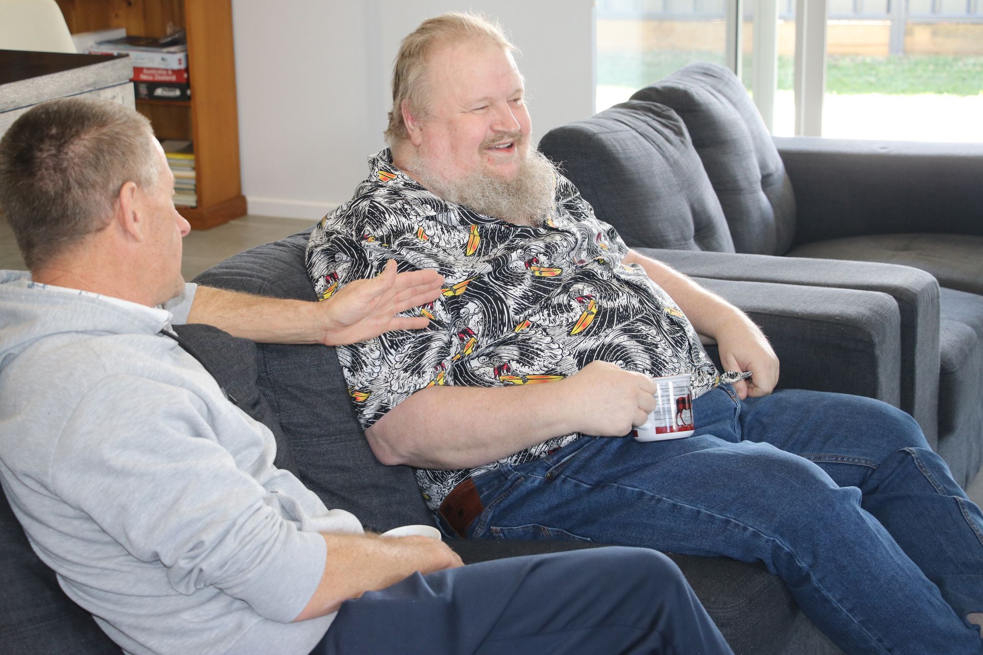 Two men are sitting on a couch talking to each other