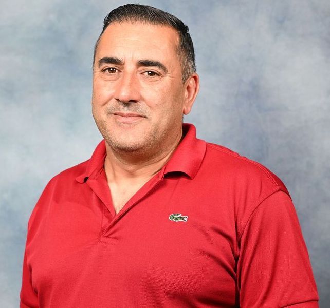 A man wearing a red shirt with a lacoste logo on it