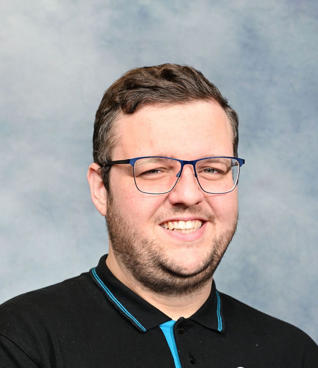 A man wearing glasses and a black shirt is smiling for the camera.