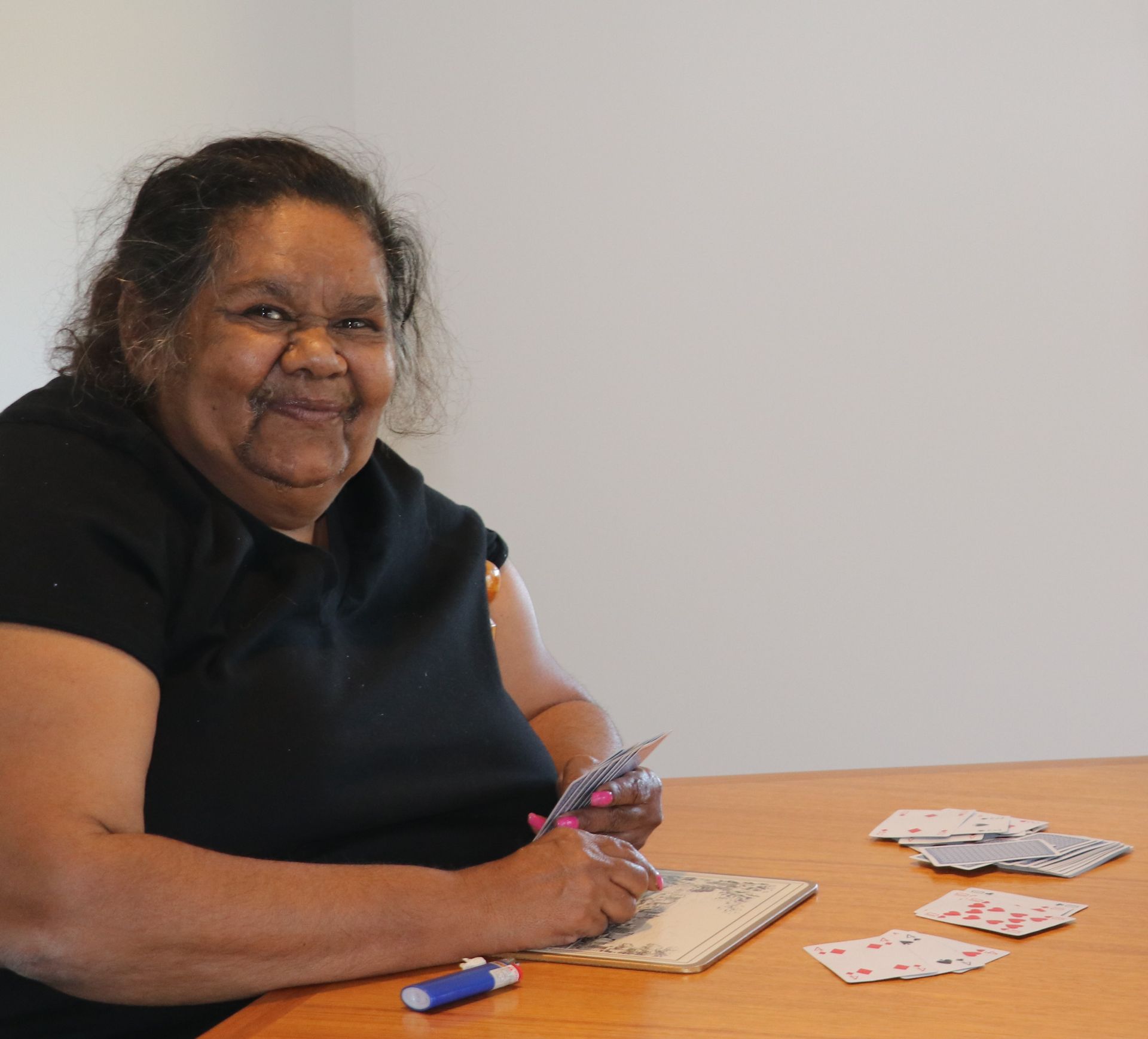 A woman in a black shirt is sitting at a table playing cards