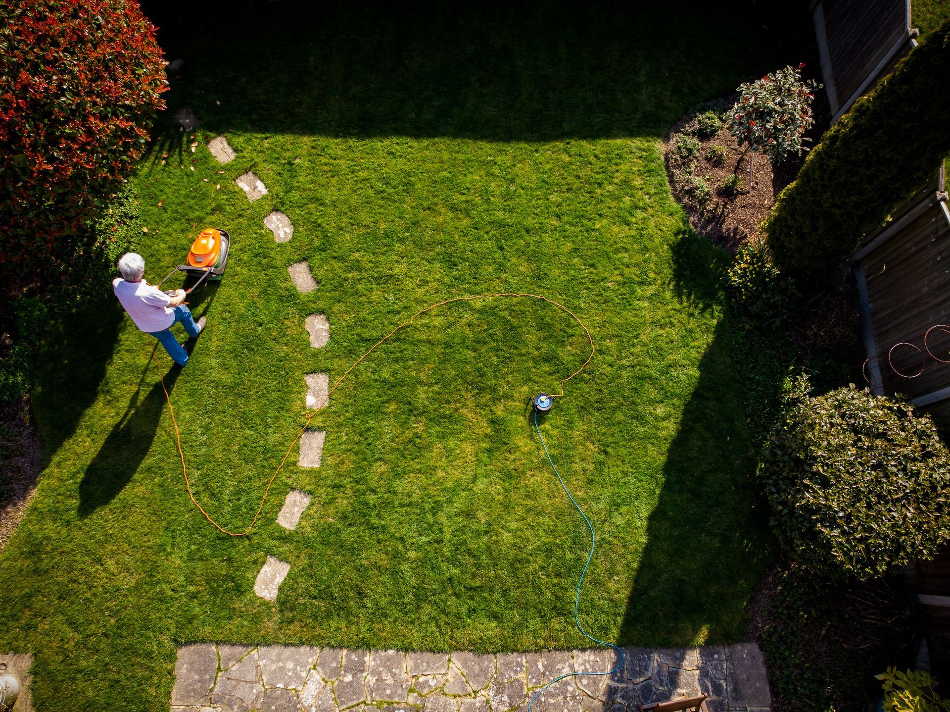 An aerial view of a person cutting a lawn with a lawn mower.