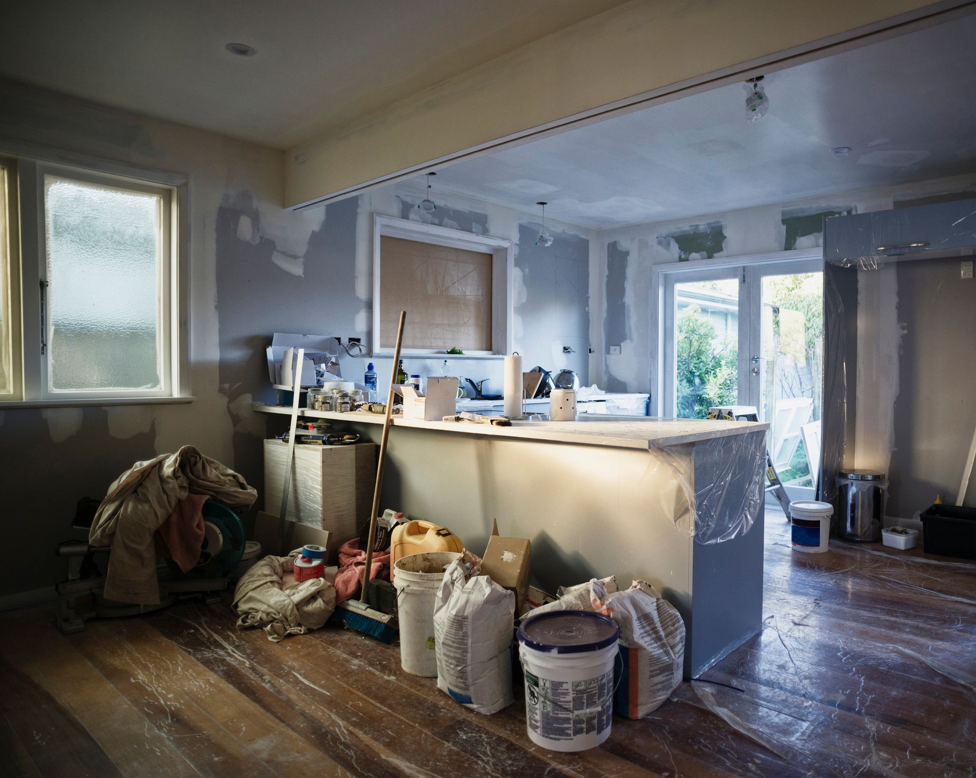 A kitchen under construction with a lot of buckets of paint on the floor.