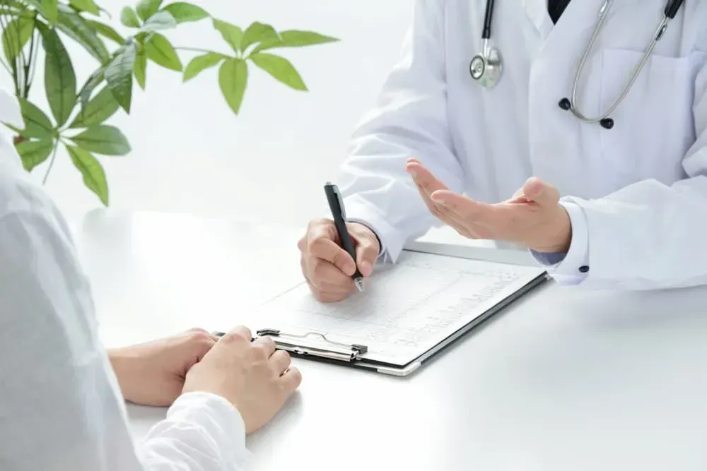 A Doctor Is Talking to A Patient While Writing on A Clipboard — Health Hub Mackay in Mackay, QLD