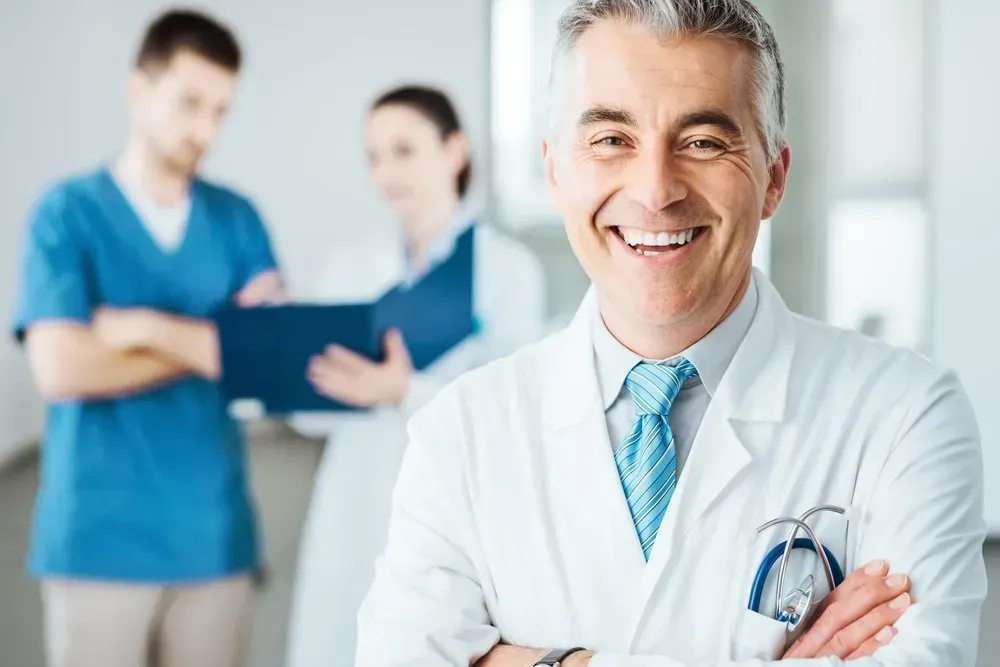 A Smiling Doctor with His Arms Crossed in Front of Two Nurses — Health Hub Mackay in Mackay, QLD